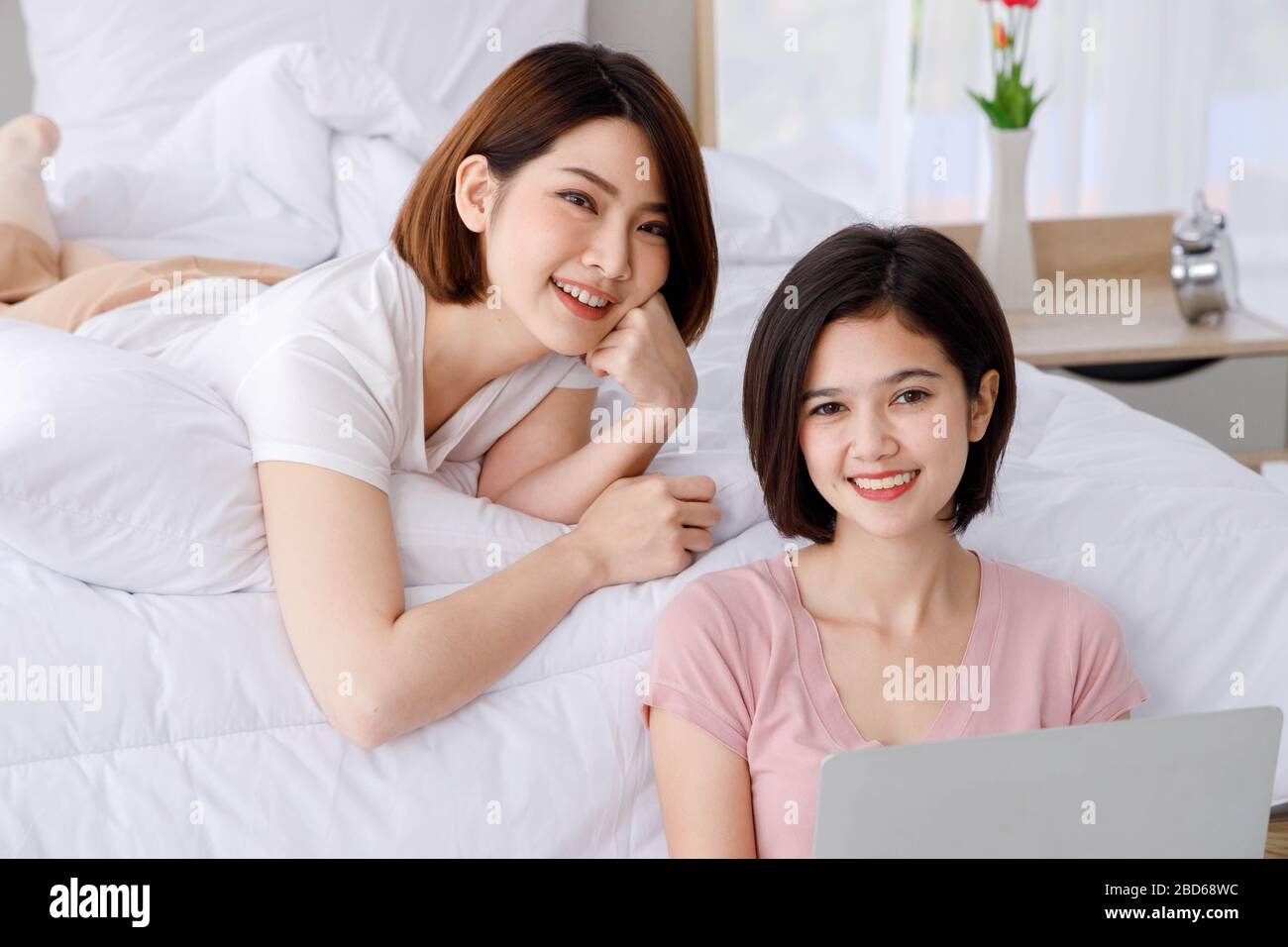 Zwei glückliche asiatische Frauen lächeln und benutzen Laptop, um im Internet zu surfen. Konzept für Teenager oder Freunde Aktivität, Lebensstil zu Hause. Stockfoto