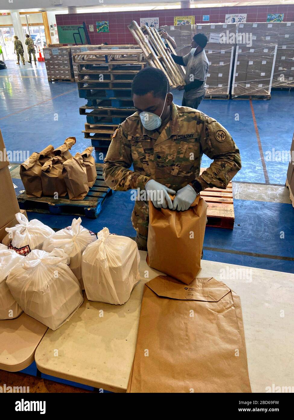 New York Army National Guard Spc. Standley Jean Baptiste, verpackt Mahlzeiten am Lebensmittelverteilungsplatz Bronx im Hunts Point Recreation Center am 6. April 2020 in Bronx, New York. Die Mahlzeiten werden an Bürger verteilt, die unter Quarantäne stehen und nicht in der Lage sind, ihre Häuser zu verlassen. Stockfoto