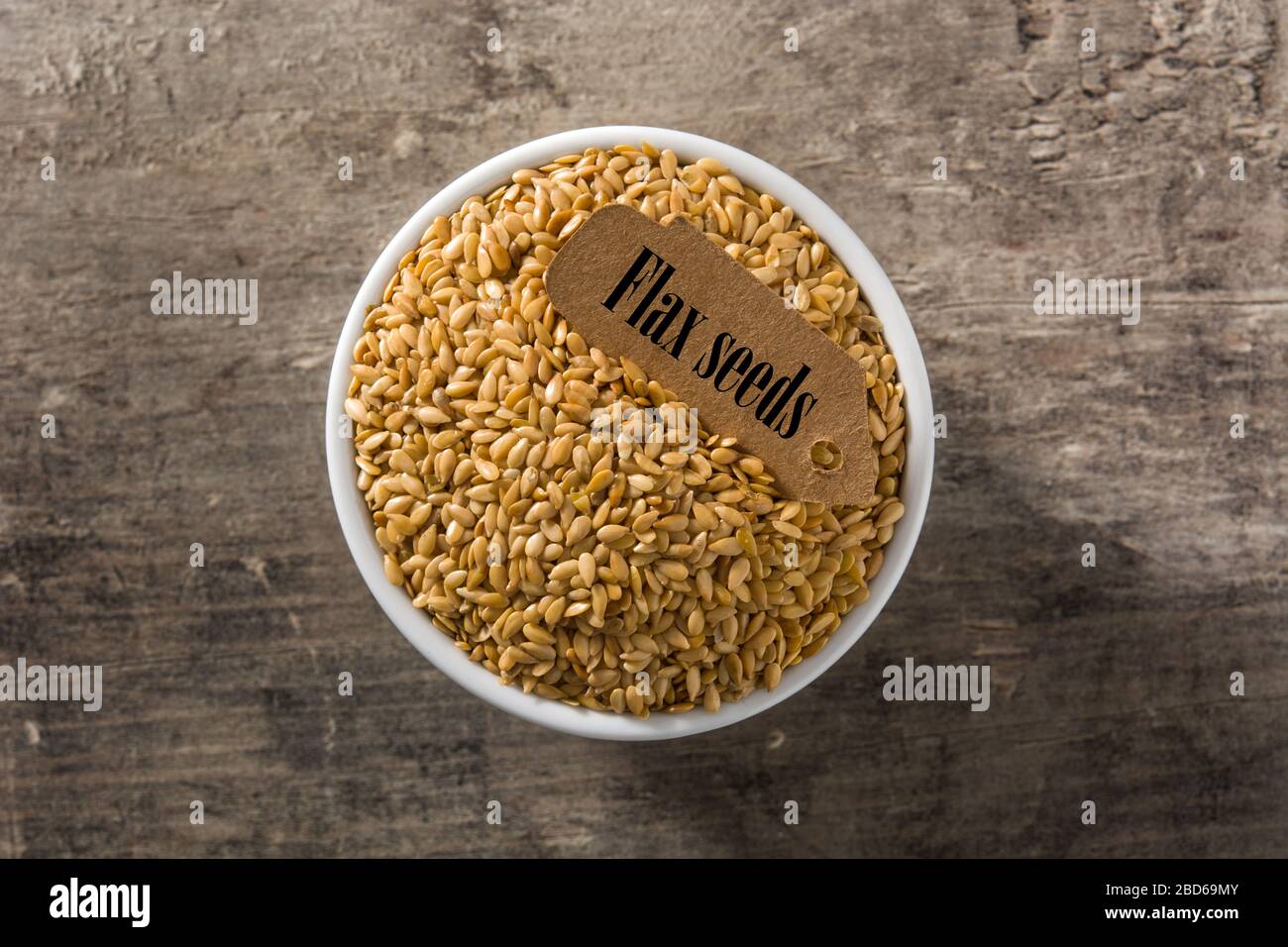 Golden Leinsamen in Weiß Schüssel auf Holztisch. Ansicht von oben Stockfoto