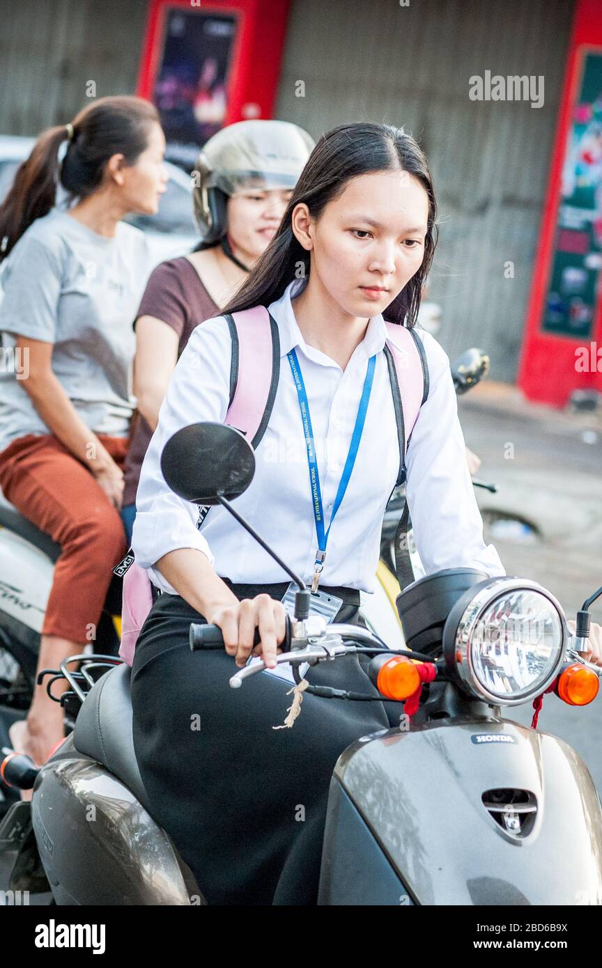 Eine junge kambodische Studentin macht sich auf ihrem Roller auf den Weg durch die Straßen von Phnom Penh. Stockfoto