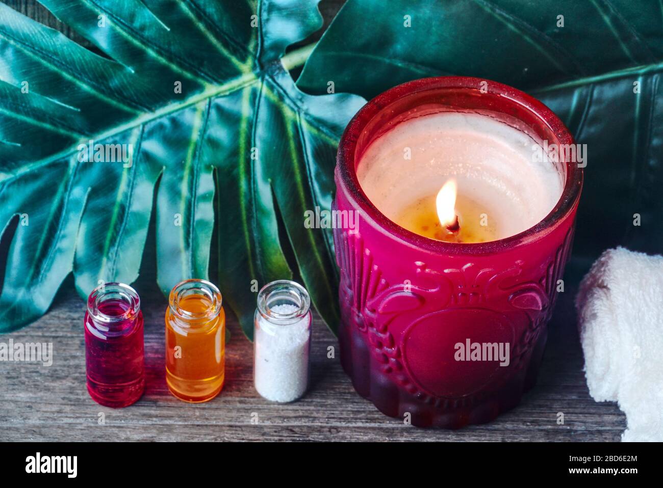 Apothecäres organisches Ölprodukt und Kerze schmücken sich mit grünem Blatt auf dem Tisch, Spa-Konzept. Stockfoto