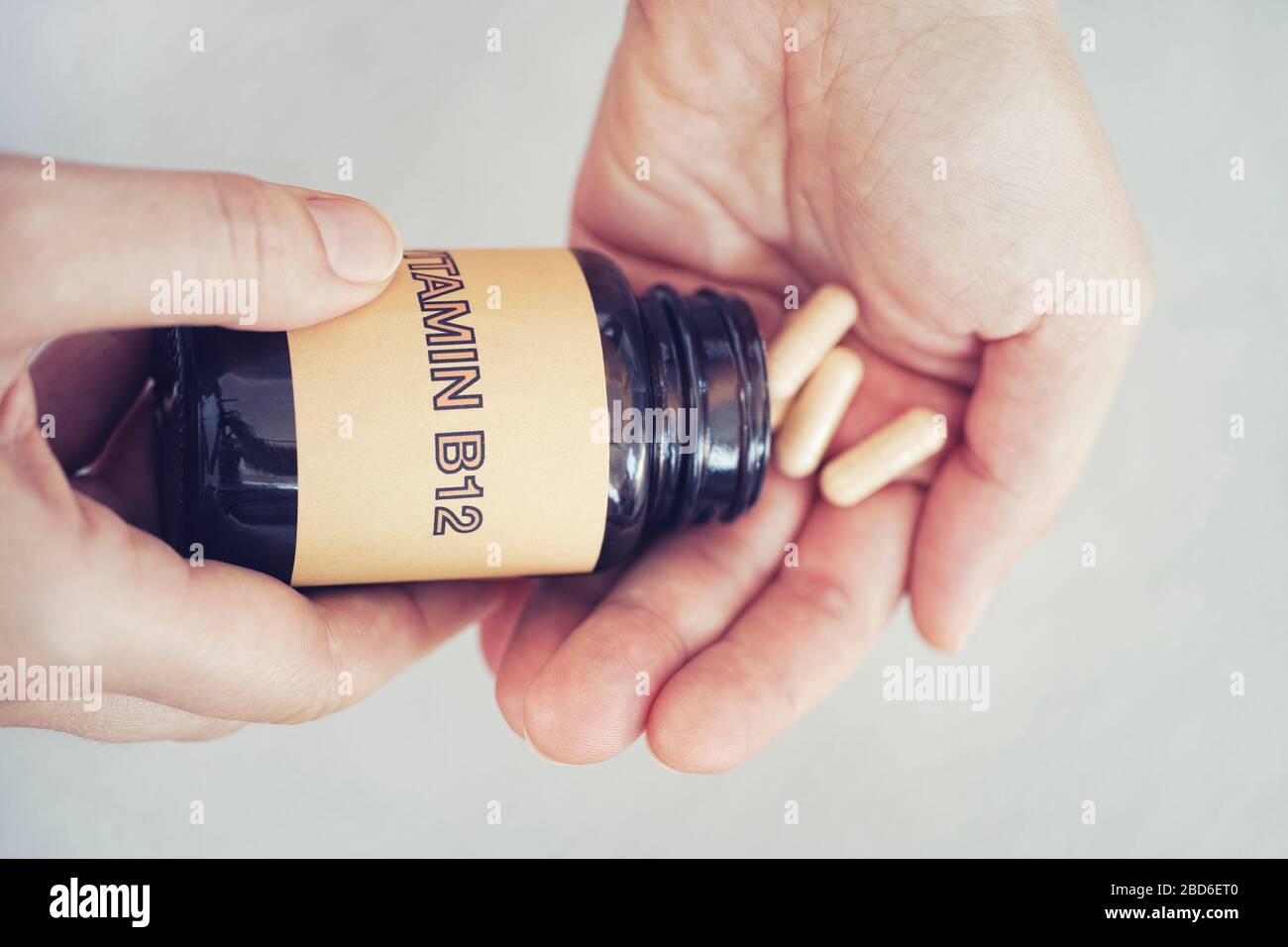 Person, die Vitamin B12-Pillen aus der Flasche herausnimmt. Nahaufnahme. Stockfoto