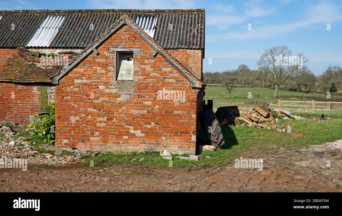 Ein verderbtes Bauernhaus und eine Scheune mit einem einstürzenden Ziegeldach Stockfoto