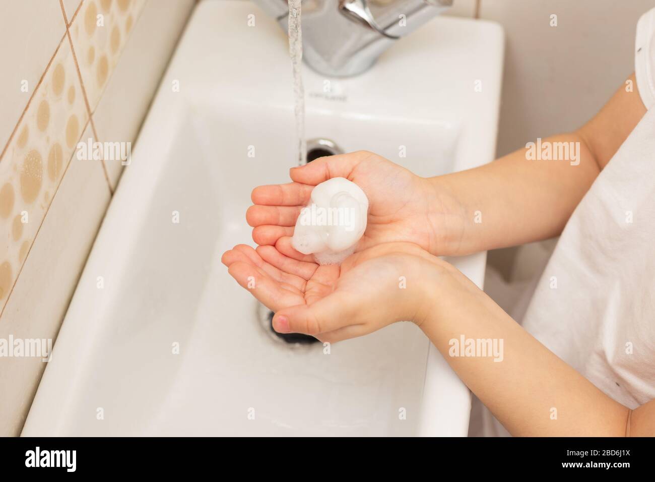 Kinderpalmen über einem Waschbecken im Badezimmer mit weißem Schaum in großen Mengen. Blick von oben. Nahaufnahme Stockfoto