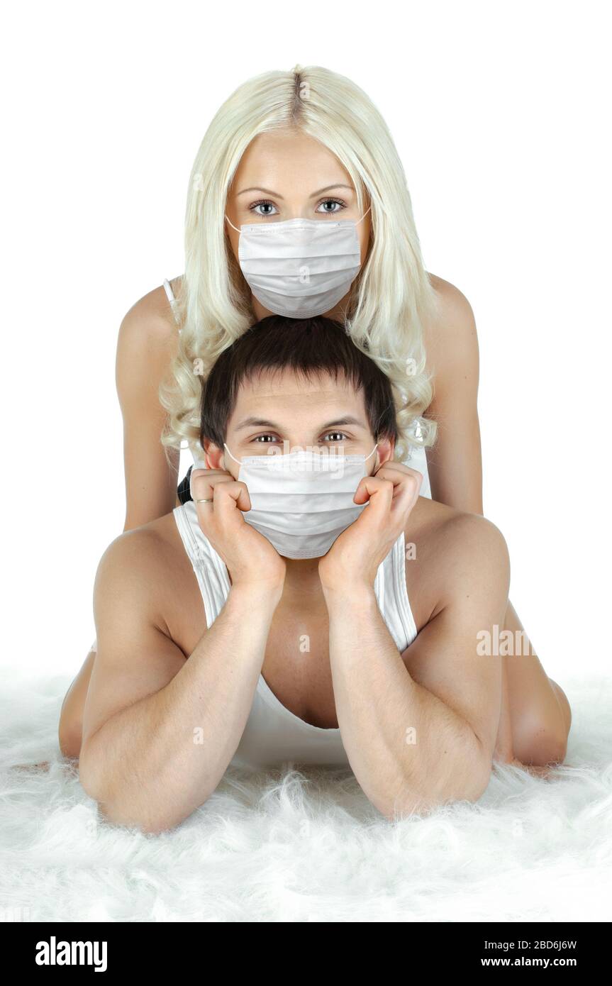 Hübsches Paar in medizinischer Maske, liegen auf dem Boden auf weißem Hintergrund, Konzept Coronavirus Covid-19 Epidemie Stockfoto