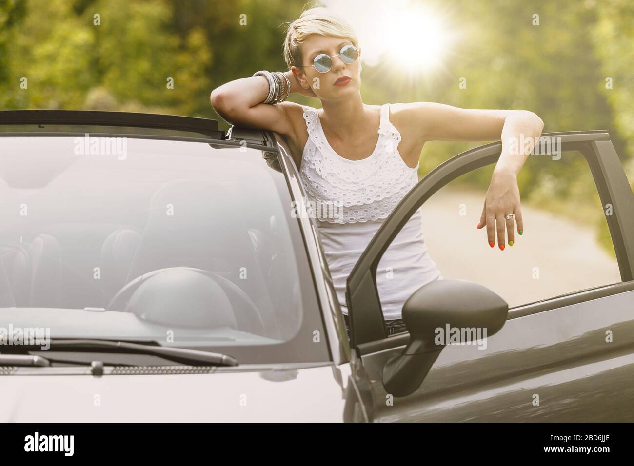 Junge blonde attraktive Frau ist bereit, in ihr Auto geben. Sie öffnet die Tür und bleibt hinter ihr. Stockfoto