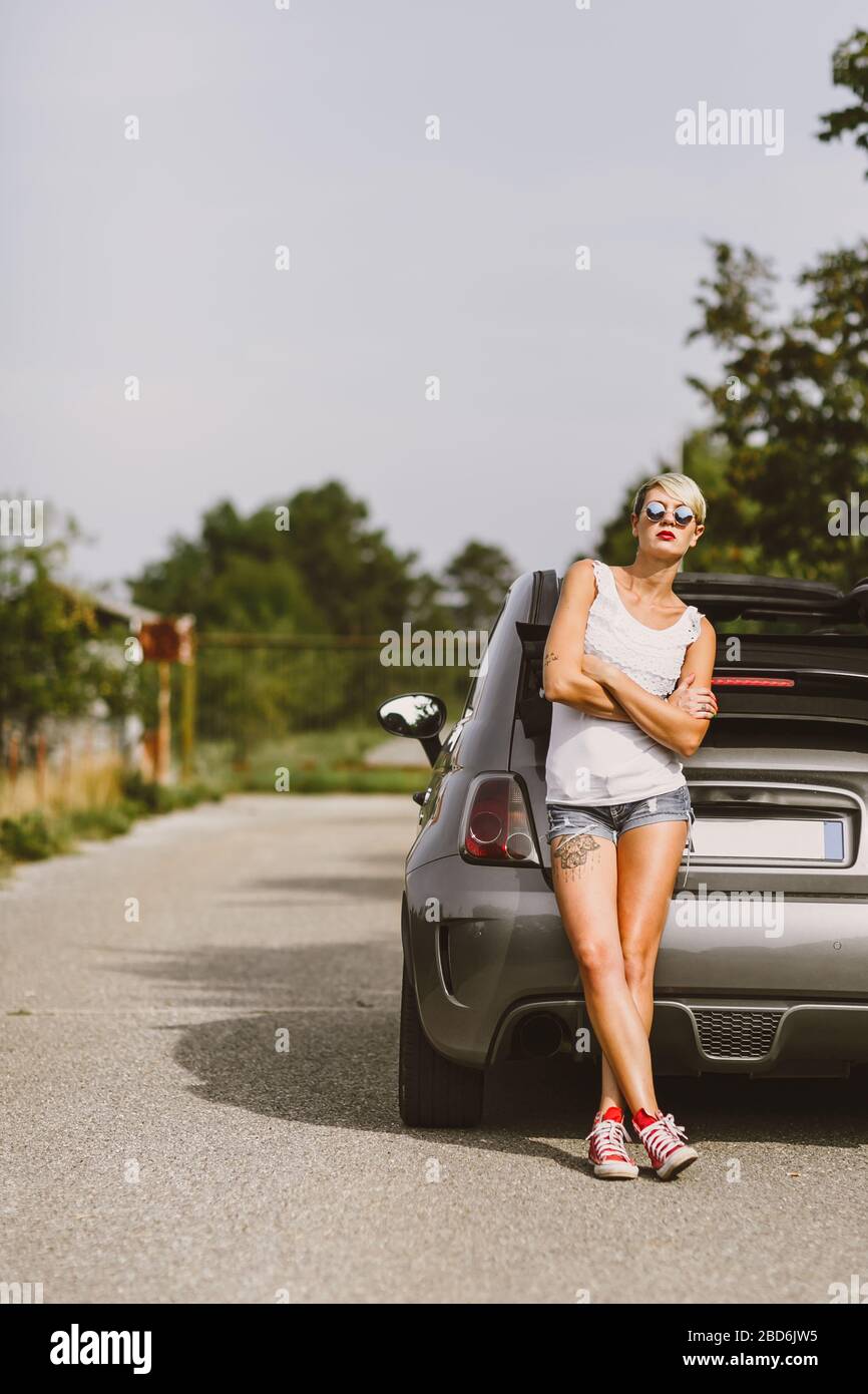 Junge hübsche modische Frau posiert auf einem Auto. Konzept junger Lifestyle. Stockfoto