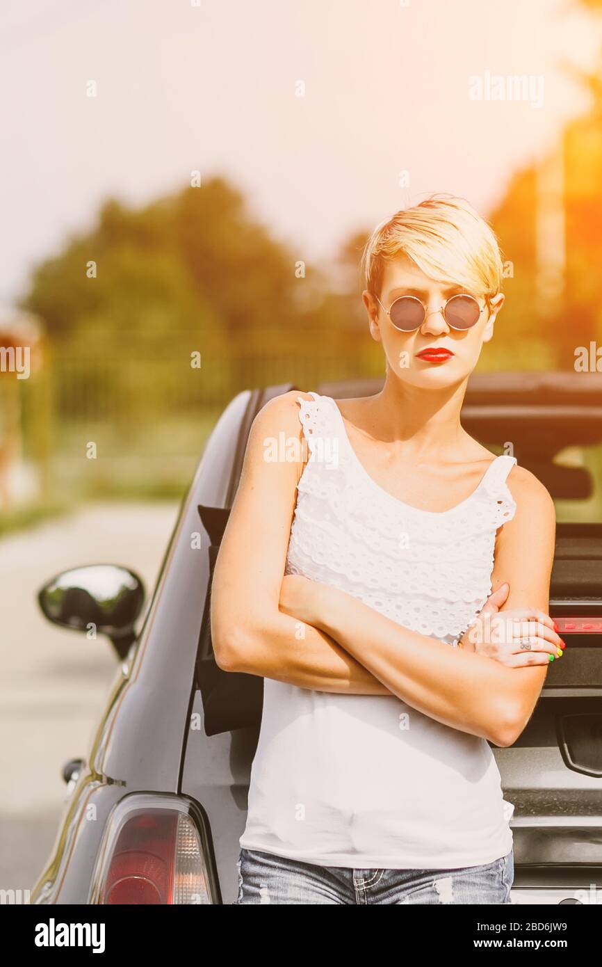 Junge hübsche modische Frau posiert auf einem Auto. Konzept junger Lifestyle. Stockfoto