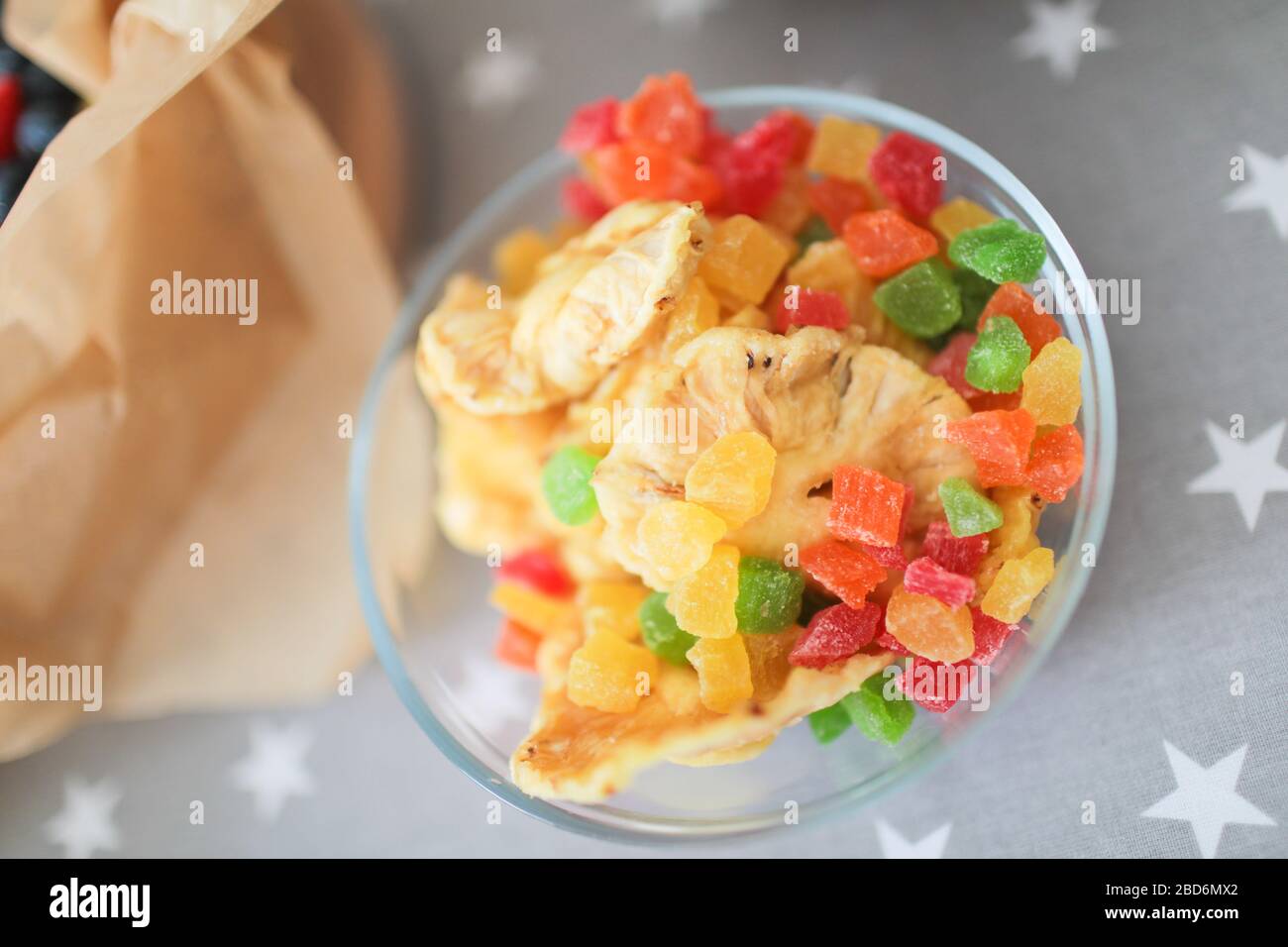 Bunte kandierte Früchte in einem transparenten, stilvollen Glas auf dem Tisch. Stockfoto