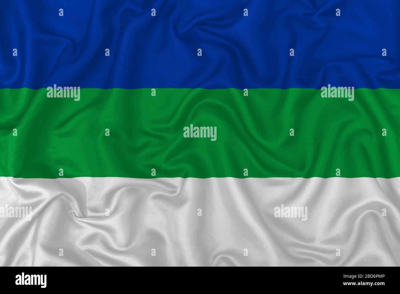 Flagge der Komi Republic auf welligem Seidentextilienstoff im Hintergrund. Stockfoto