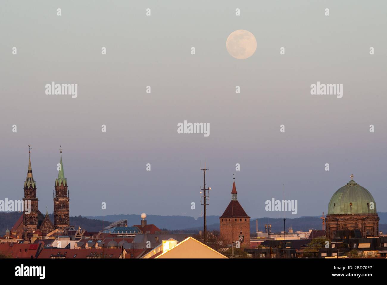 Nürnberg, Deutschland. April 2020. Der Mond erhebt sich als sogenannte Supermond, im Vordergrund sind die Türme der Kirche St. Laurentius (l), der Weiße Turm (M) und die Kuppel der Kirche St. Elisabeth zu sehen. Der Mond erreicht in der Nacht vom 7. Auf den 8. April als Vollmond seinen Perigäum, also den Punkt, der dem Erdorbit am nächsten liegt und erscheint daher dem menschlichen Beobachter besonders groß. Credit: Daniel Karmann / dpa / Alamy Live News Stockfoto