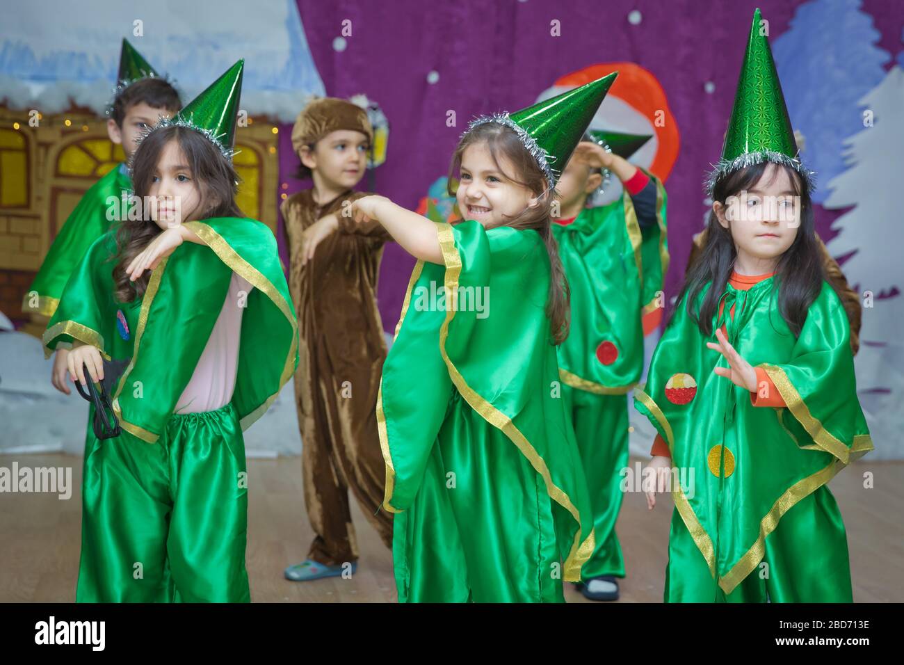 Die Kinder sind grün gekleidet als pinocchio. Kindergartenteilnehmer nehmen an einer Neujahrsveranstaltung Teil. Kinder in festlich grünen Kostümen von gekleidet Stockfoto