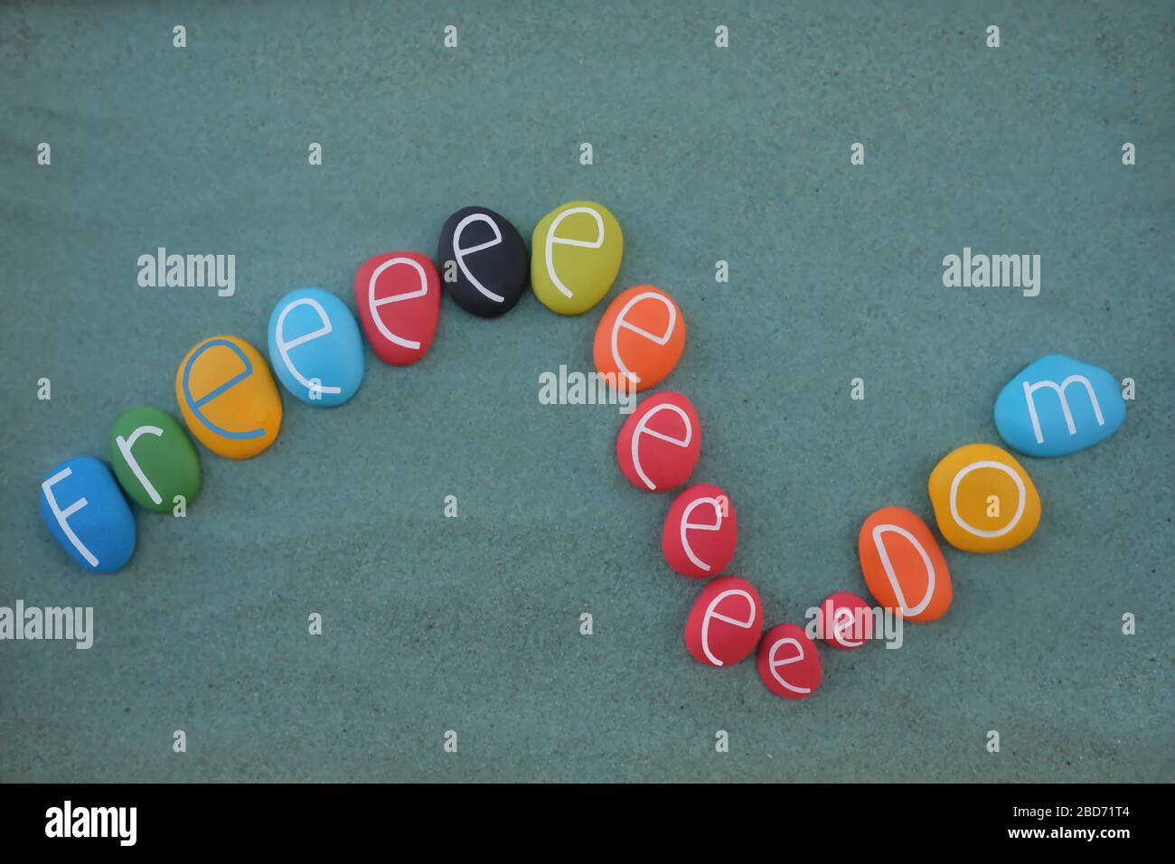 Freedom Scream mit bunten Steinbuchstaben über grünem Sand komponiert Stockfoto