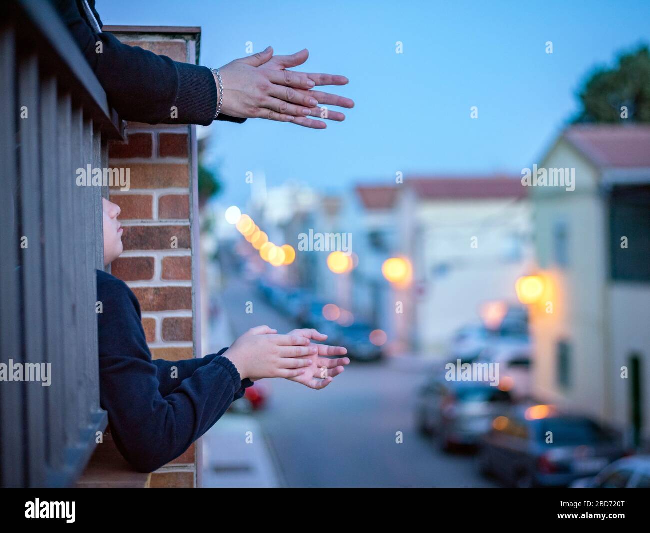 Die Hände klatschen auf einem Balkon mit Blick auf eine Straße, während die Beleuchtung eingeschaltet ist Stockfoto