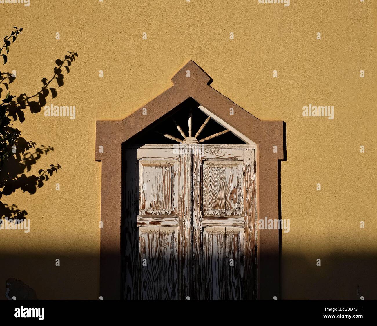 Eine Wand mit Sonne und Schatten und Ziertür. Stockfoto