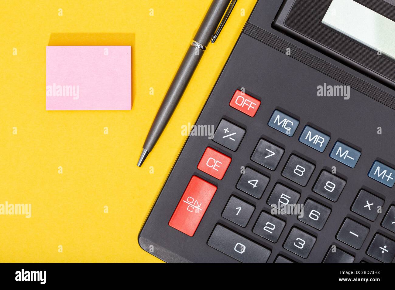Taschenrechner, Stift und leerer Haftnotiz auf gelbem Hintergrund.  Hintergrund für Wirtschafts- oder Geschäftskonzepte. Kopierbereich.  Verspotten Sie sich Stockfotografie - Alamy