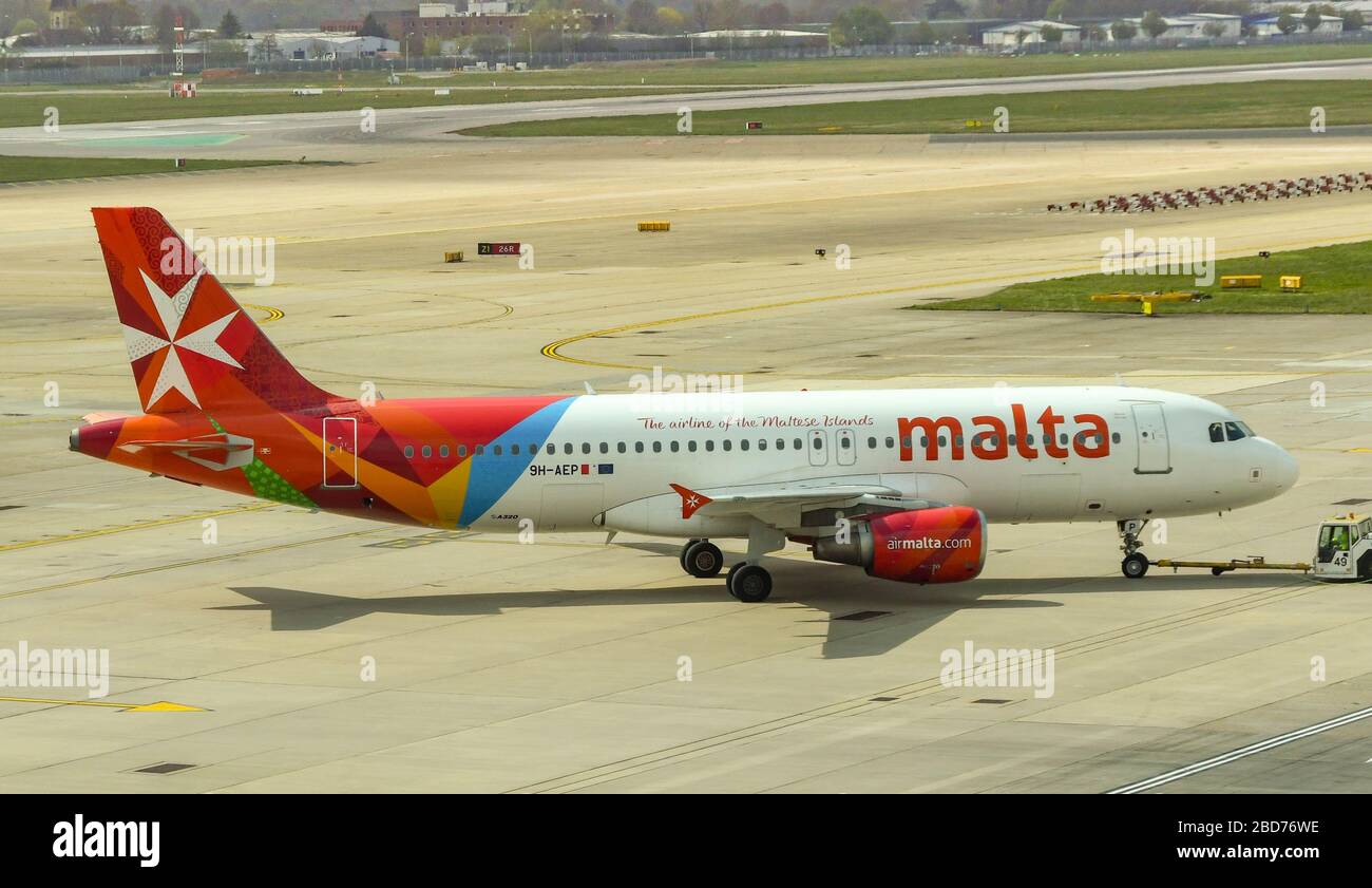 FLUGHAFEN LONDON-GATWICK - APRIL 2019: Airbus A320-Jet der Air Malta wird bei der Abfahrt vom Flughafen London-Gatwick von einem Schlepper zurückgedrängt. Stockfoto