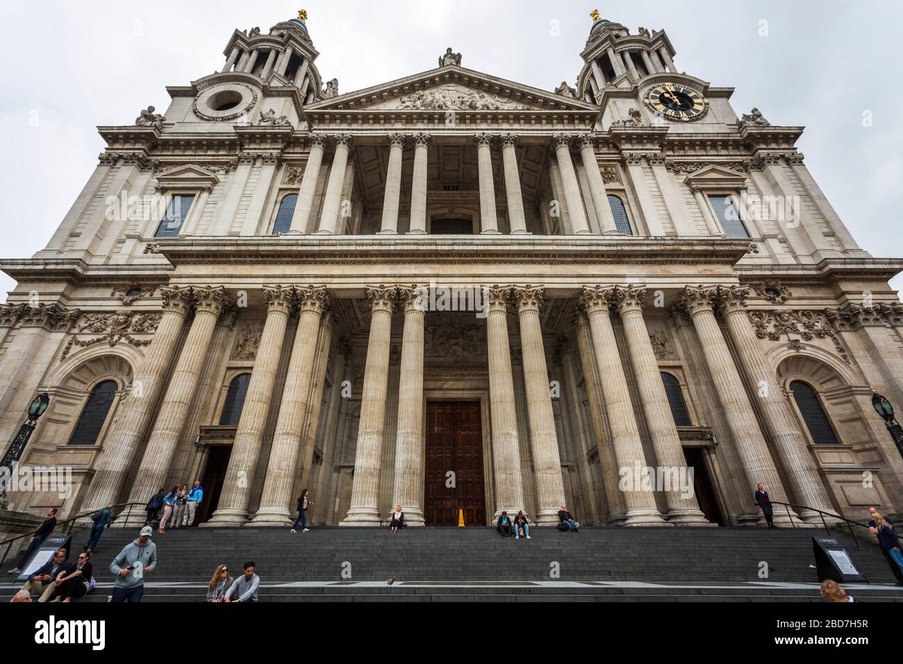 Blick auf die St. Paul's Kathedrale mit den Menschen, die an einem trüben Morgen an der Eingangstreppe sitzen. Stockfoto