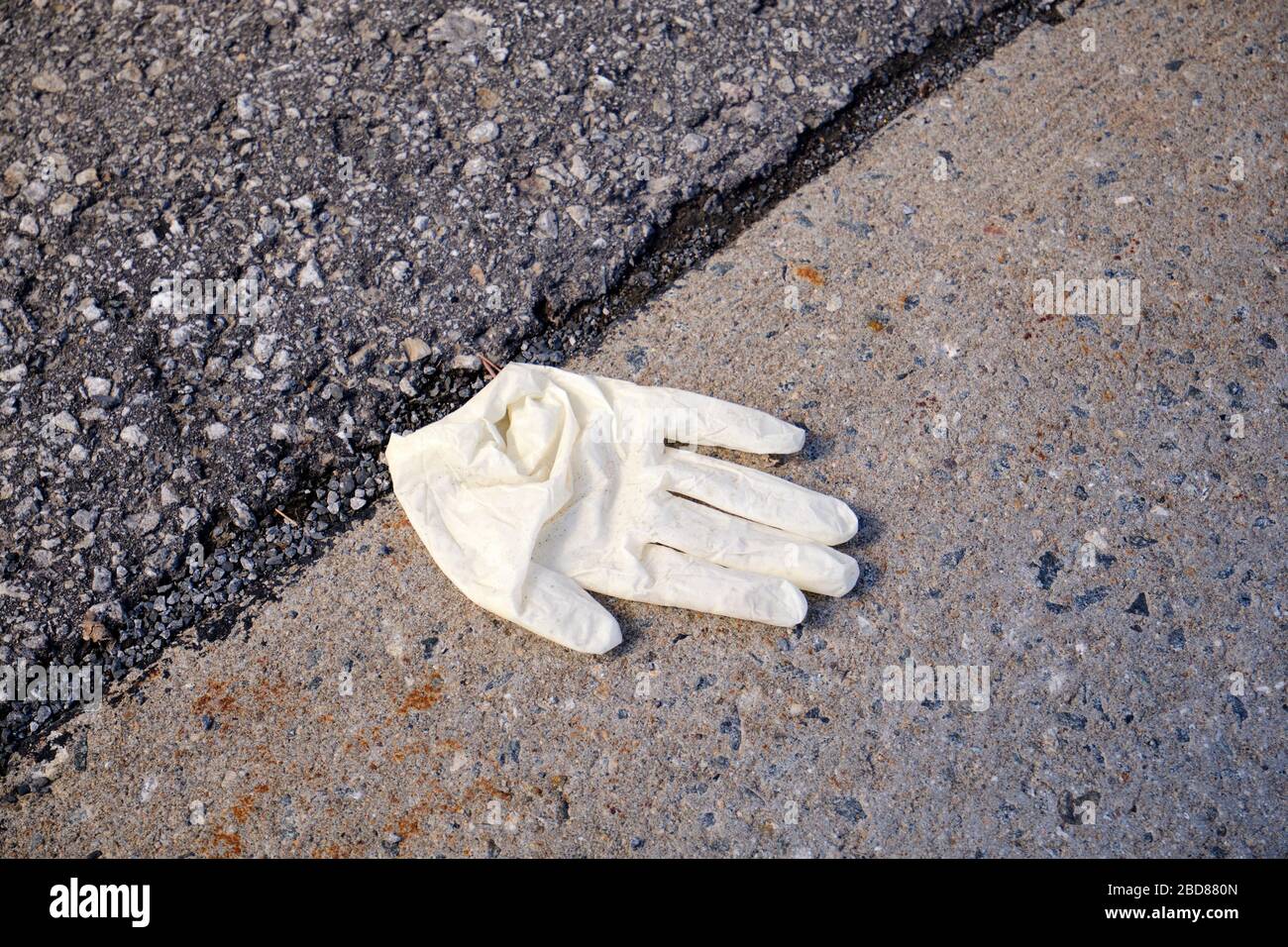 Ausrangierte Schutzhandschuhe aus weißem Latex auf dem Bürgersteig in Montreal, Stockfoto