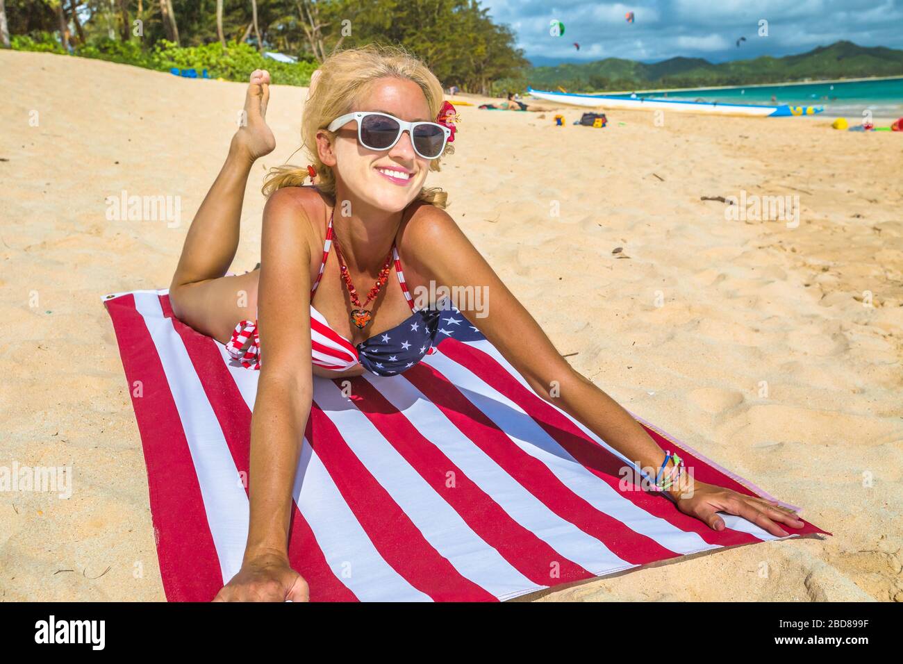 Sonnenbändchenschild während der Covid-19-Pandemie. Weißes Gesicht für die Verwendung einer sanitären Maske für Frauen mit amerikanischem Flaggentuch im hawaiischen Lanikai Beach, mit Stockfoto