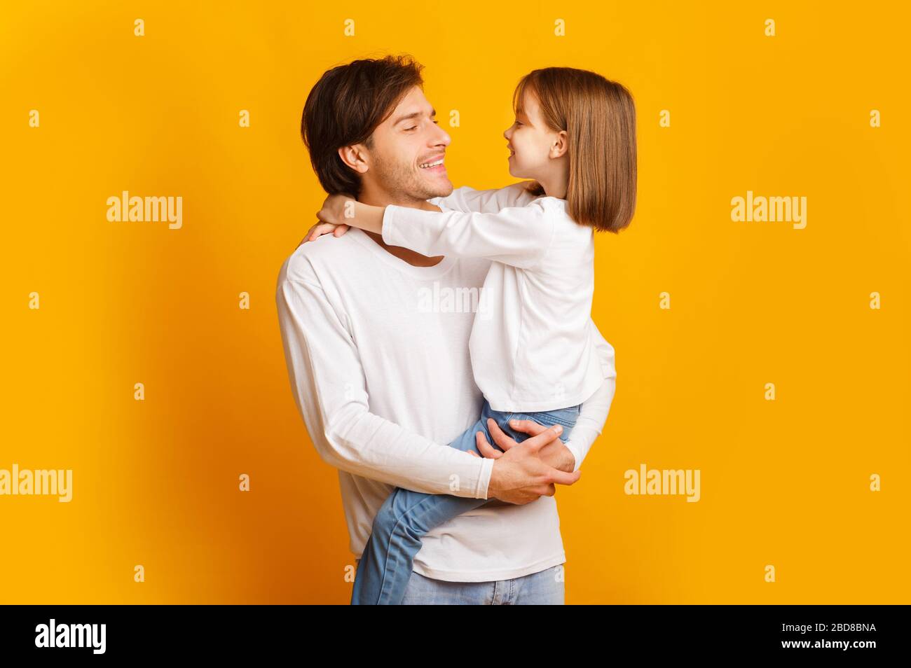 Fröhlicher Vater und Tochter posieren zusammen auf gelbem Hintergrund Stockfoto