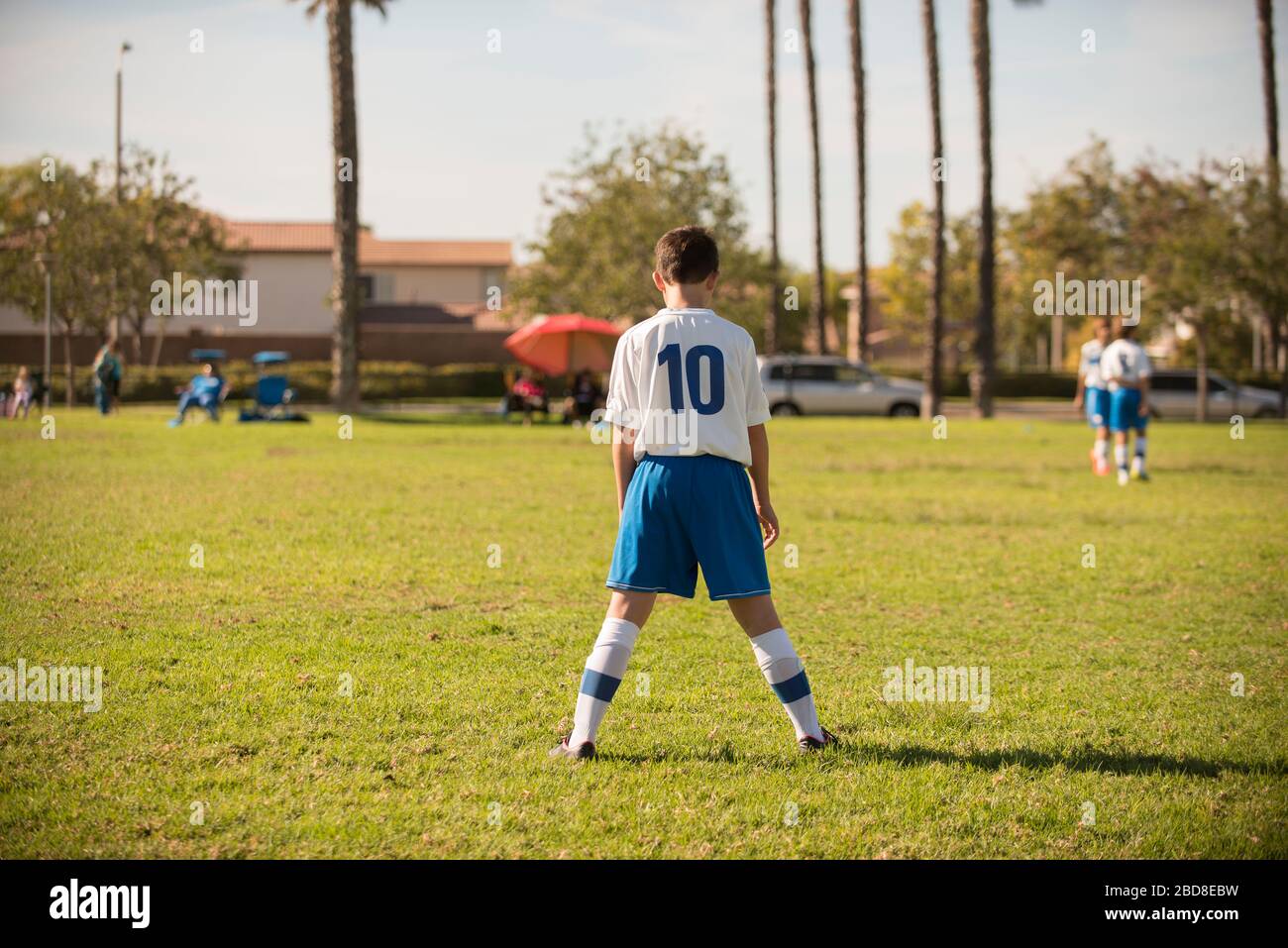 Junger Spieler in Fußballuniform, der im Park streikt Stockfoto