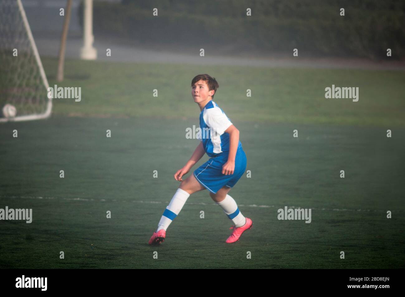 Teen Fußballspieler bereit, auf einem nebligen Feld zu verteidigen Stockfoto