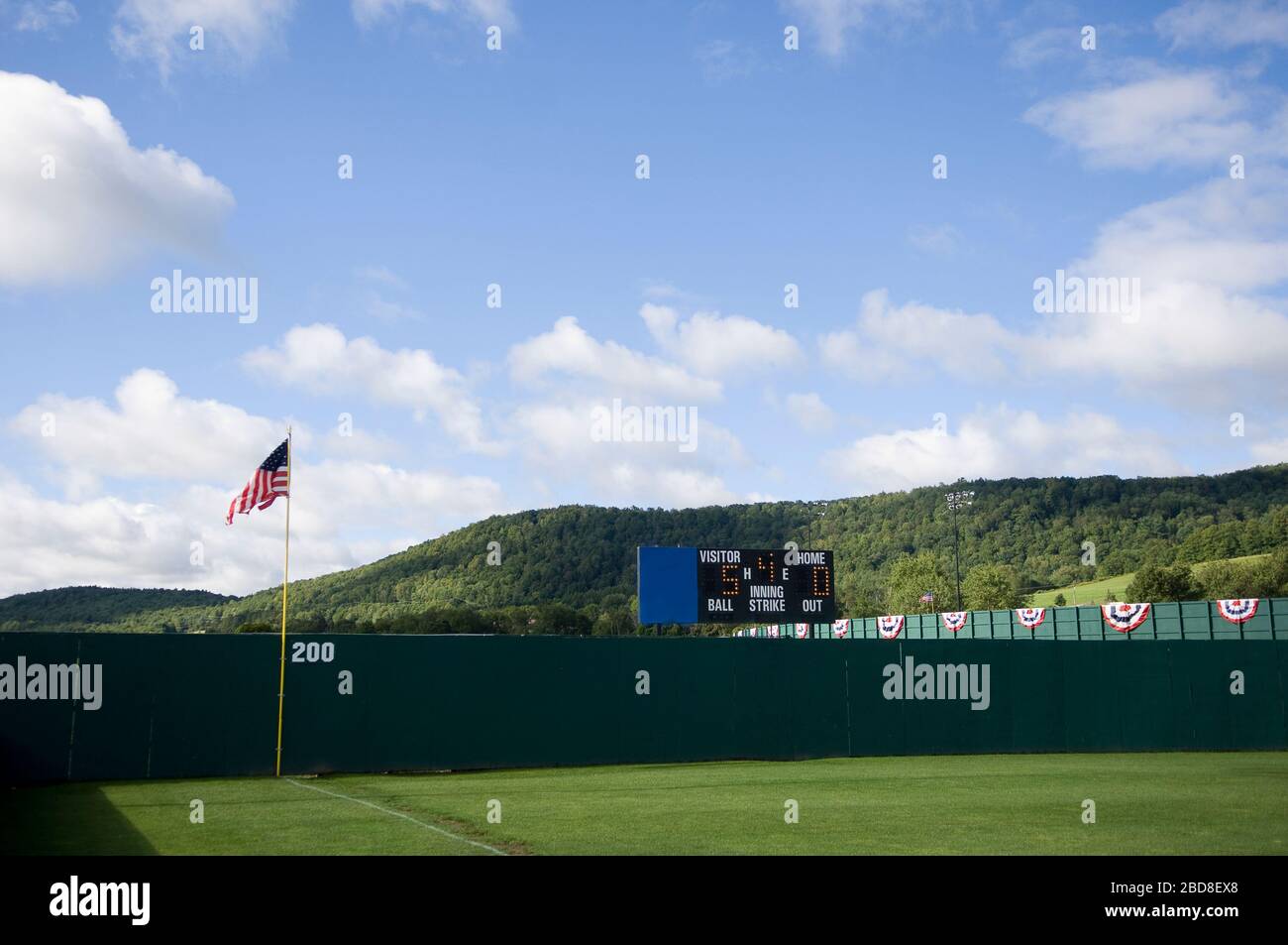 Baseball Außenfeld Zaun und rollenden Hügel mit Anzeigetafel und amerikanische Flagge Stockfoto
