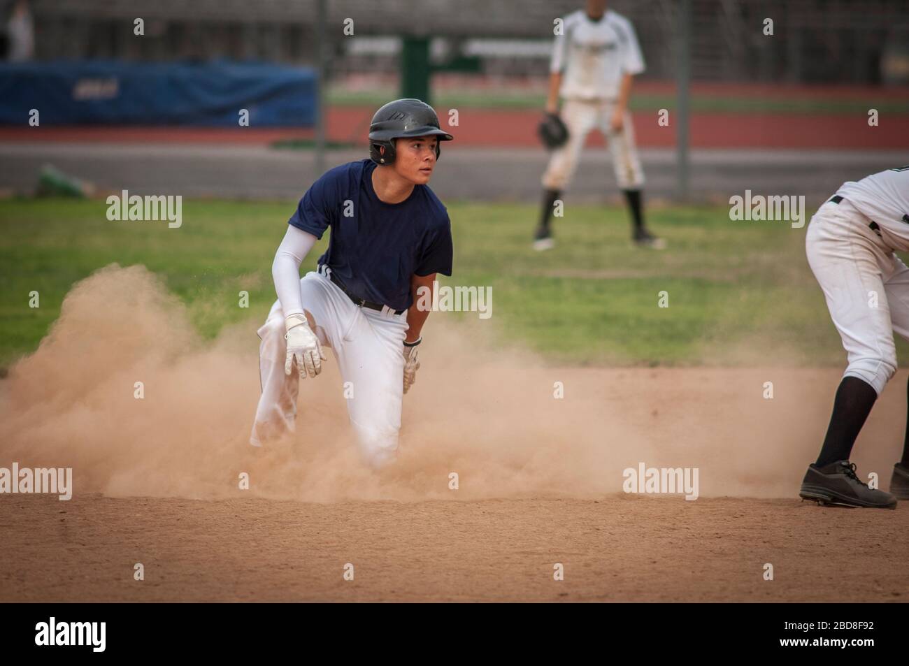 Junger Baseballspieler in Staubwolke nach dem Gleiten in die zweite Basis Stockfoto