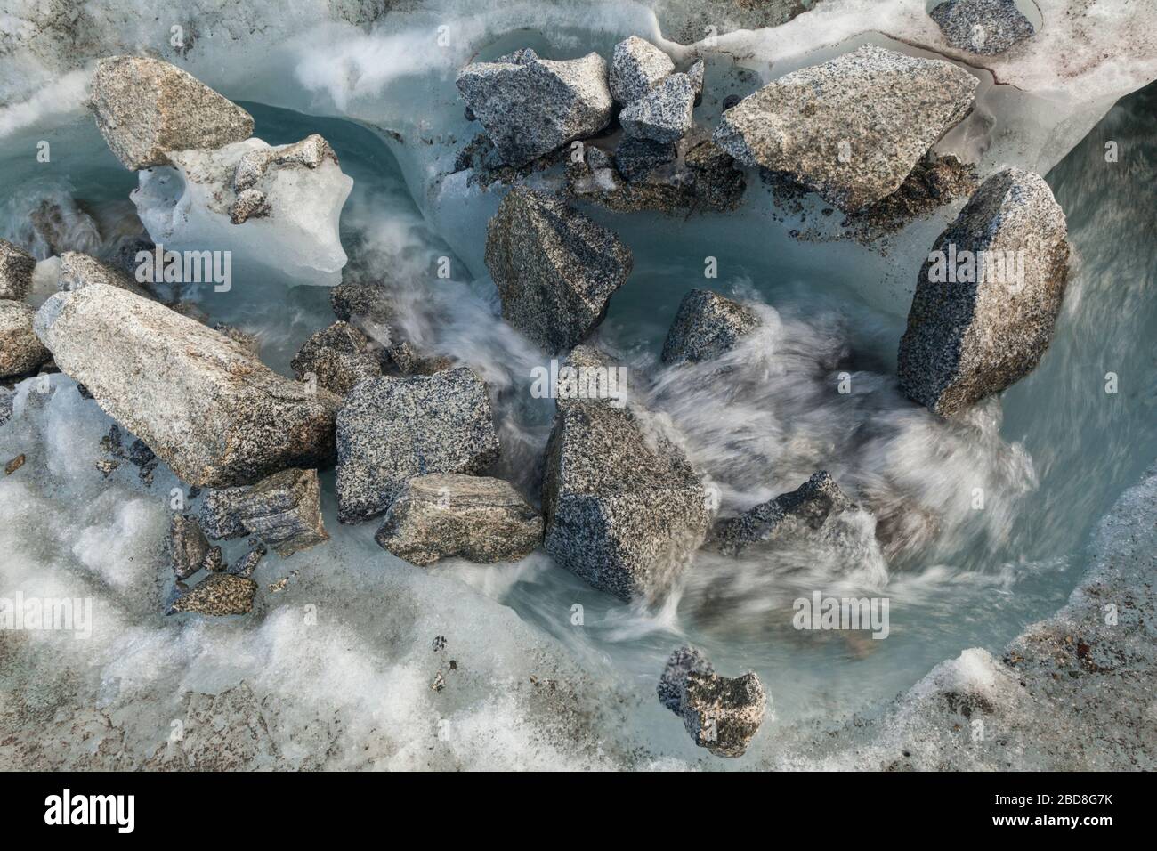 Glazialer Schmelzwasserstrom mit Felsbrocken, die sich auf der Oberfläche des Snowbird-Gletschers, der Talkeetna Mountains, Alaska, ablagern. Stockfoto