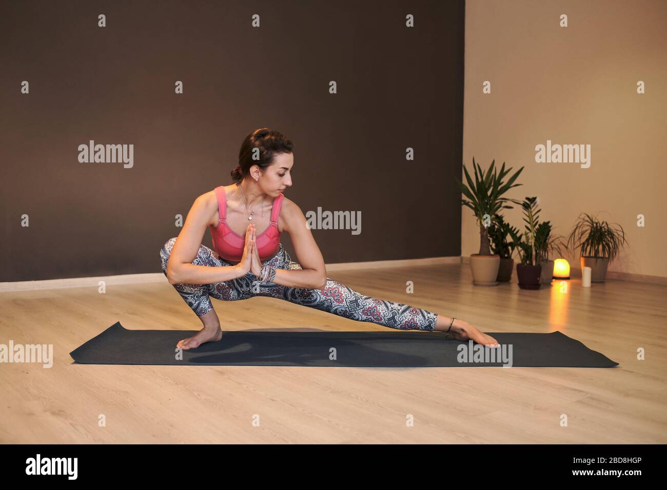 Junge Frau beim Yoga auf Yogamatte in stimmungsvollem Yoga-Studio Stockfoto