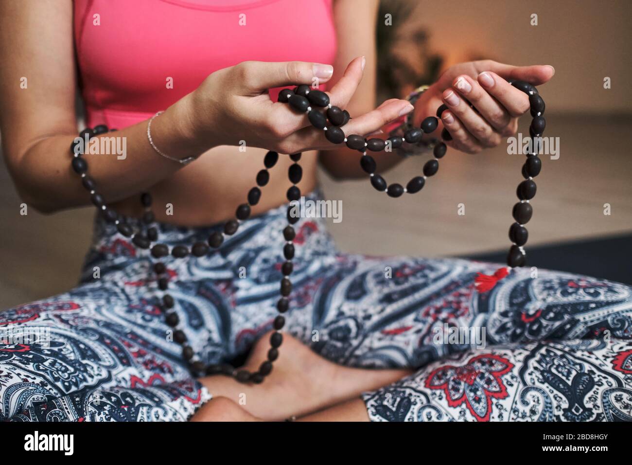 Junge Frau meditiert allein mit einem Yoga-Studio für Yoga mit Perlen Stockfoto