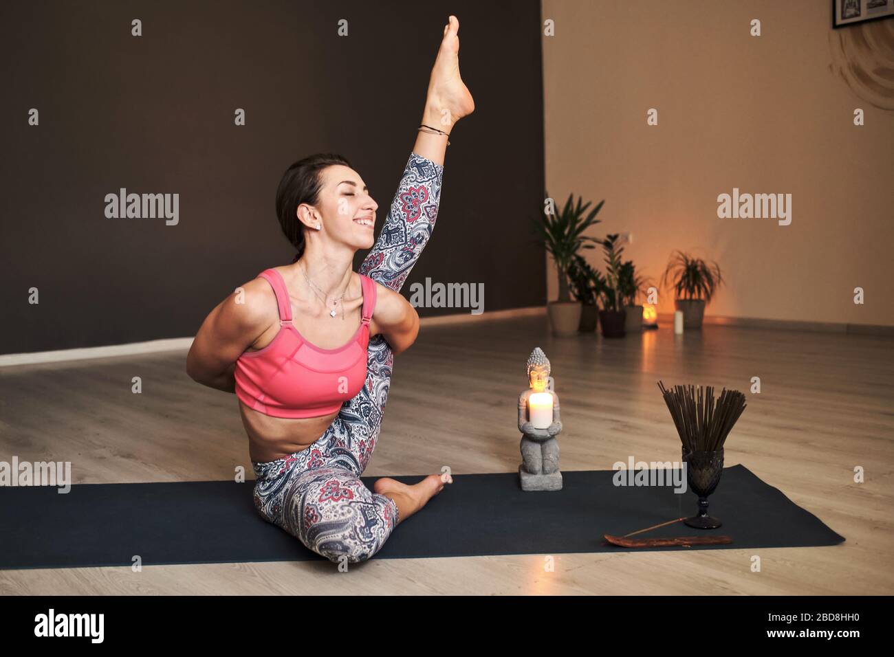 Junge Frau beim Yoga auf Yogamatte in stimmungsvollem Yoga-Studio Stockfoto