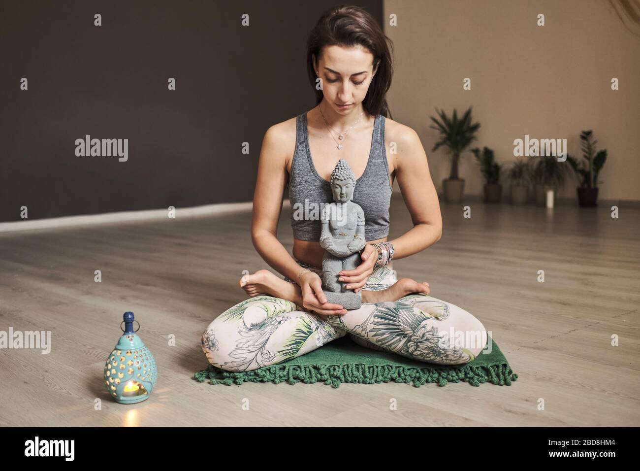 Junge Frau meditiert allein im Yoga-Studio mit Duftlampe und Budda Stockfoto