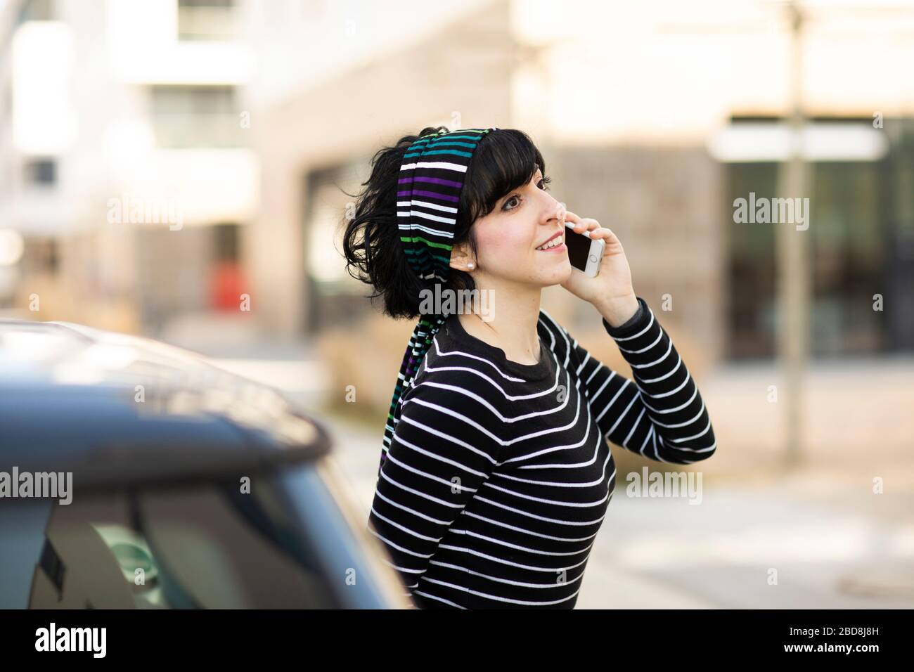 Junge Frau vor einem Auto mit Smartphone Stockfoto