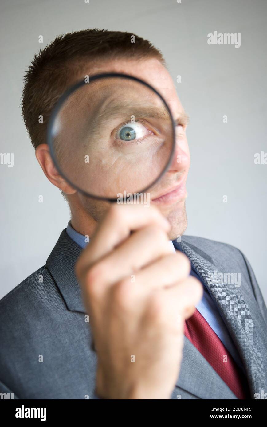 Verdächtiger Geschäftsmann mit vergrößertem Auge suchen durch Lupe Stockfoto