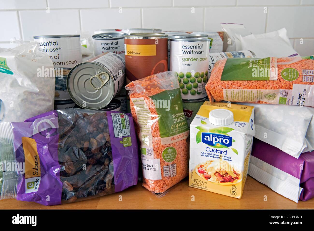 Dosen und Pakete von getrockneten Lebensmitteln stapeln sich auf der Arbeitsfläche der Küche nach der Lieferung nach Hause. Vorräte aufgrund der Sperrung der Coronavirus Corvid 19-Pandemie. Stockfoto