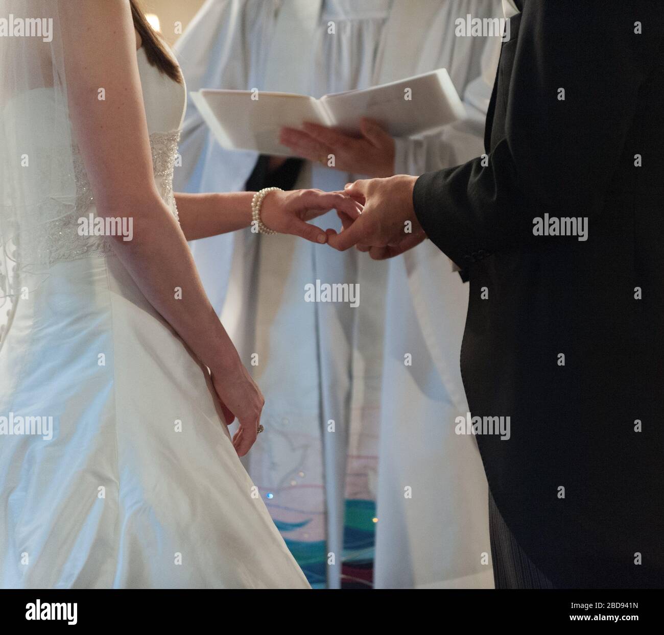 Braut und Bräutigam halten die Hände am Altar vor dem Amtsträger oder Priester Stockfoto
