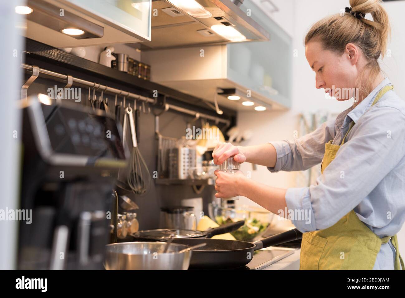Wohnen Sie zu Hause Hausfrau Frau, die in der Küche kocht, in einem Topf salzt und Essen für das Familienessen zubereitet. Stockfoto