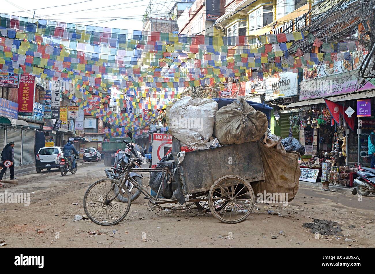 Kathmandu, Nepal - 5. März 2018: Illustrative Editorial zeigt die staubige Straße von Kathmandu mit ihren alten rostigen Fahrrädern und bunten Flaggen Stockfoto