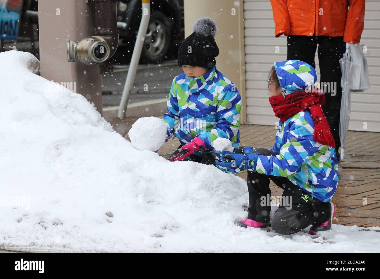 Zwei Kinder spielen mit Schnee Stockfoto
