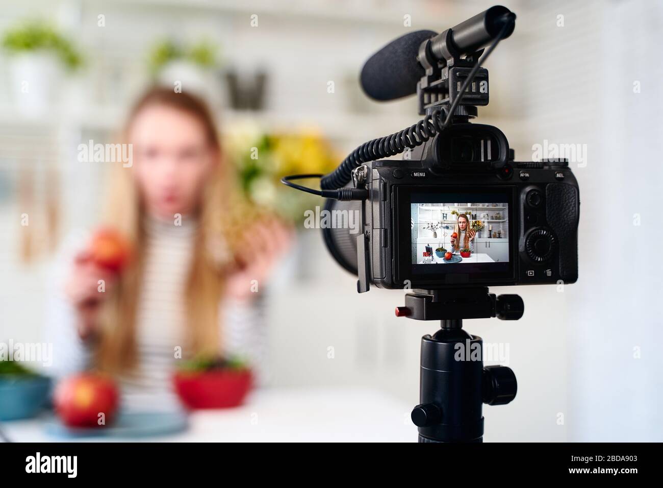 Anzeige von Video-Blog für die Aufnahme von Kameras für die Blogger-Frau mit apple, Ananas in Küchenstudio über gesunde vegane Ernährung sprechen. Einflussnehmer Stockfoto