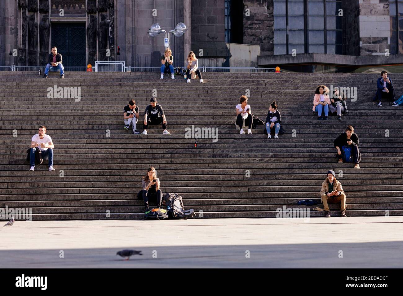 Köln, Deutschland. April 2020. Kolner halten während der Ausstiegsbeschränkungen in der Koronakrise die Mindestdistanz ein und genießen die Sonne auf der Domtreppe. Koln, 7. April 2020 - weltweite Nutzung Credit: Dpa/Alamy Live News Stockfoto
