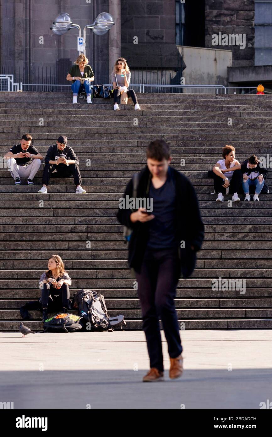 Köln, Deutschland. April 2020. Kolner halten während der Ausstiegsbeschränkungen in der Koronakrise die Mindestdistanz ein und genießen die Sonne auf der Domtreppe. Koln, 7. April 2020 - weltweite Nutzung Credit: Dpa/Alamy Live News Stockfoto
