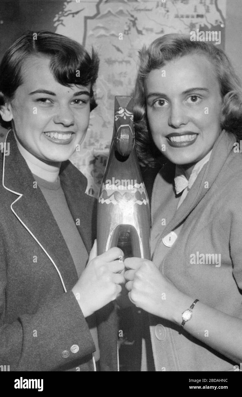 'Svenska: Jo Ann Johnson och Janet Renquist beskådar en Dalahäst.Oh es ist schön. . . Ich bin so glücklich, hier zu sein. . . ljöd det i korus från de 16 söta och pigga amerikanskor, som under mr. Tels Langsjoen och hans makas vingars skugga kom till Sverige på onsdagen som Bernadottestippendiater. De sexton studerar vid Gustavus Adolphus College i Minesota och representerar många olika fack från gymnasten till juristen. En blonde ung Dam hade redan inriktat sig på en karriär som skolkslärarinna, en annan på sjuksköterskeyrket, som hon ansåg vara en trygg och stadig bana. I Stockholm har de omhänder Stockfoto