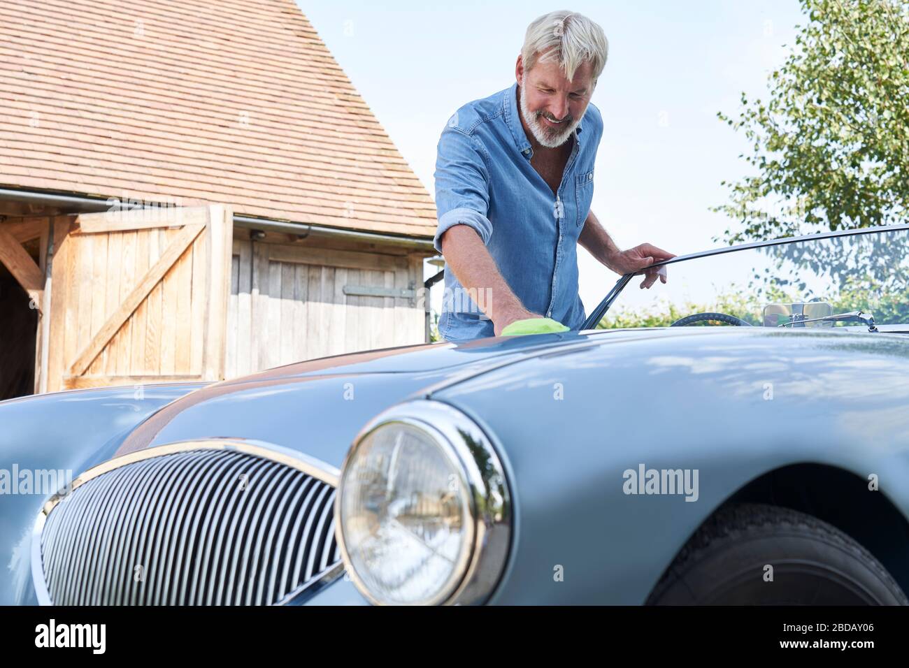 Reifer Mann Polieren restauriert Sportwagen im Freien zu Hause Stockfoto