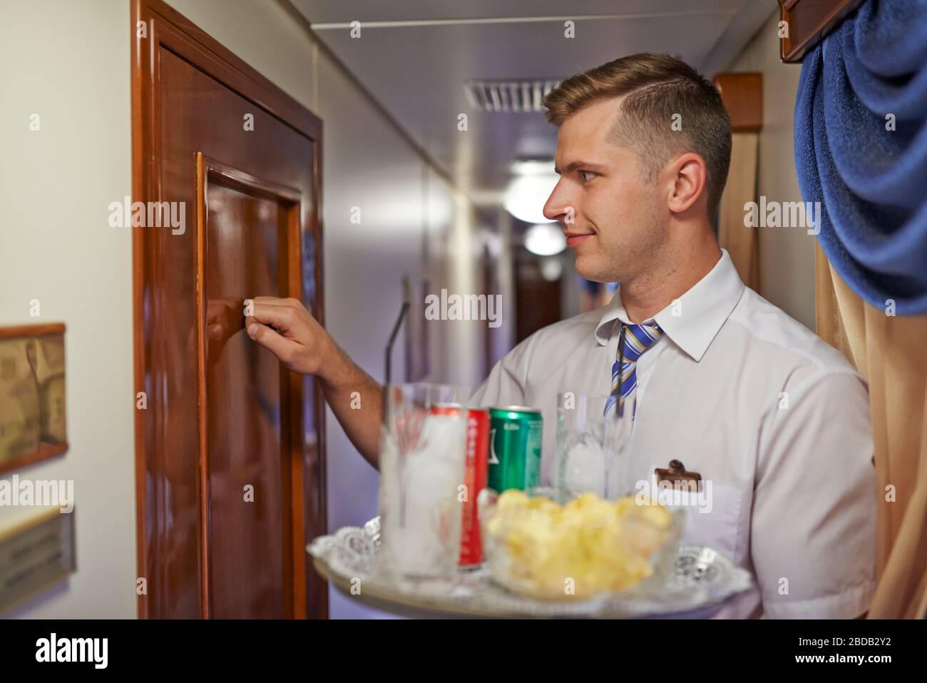 Zimmerservice in einem luxuriösen Transsibirischen Express; Leiter; Getränkeablieferung; Reinigung des Zimmers Stockfoto