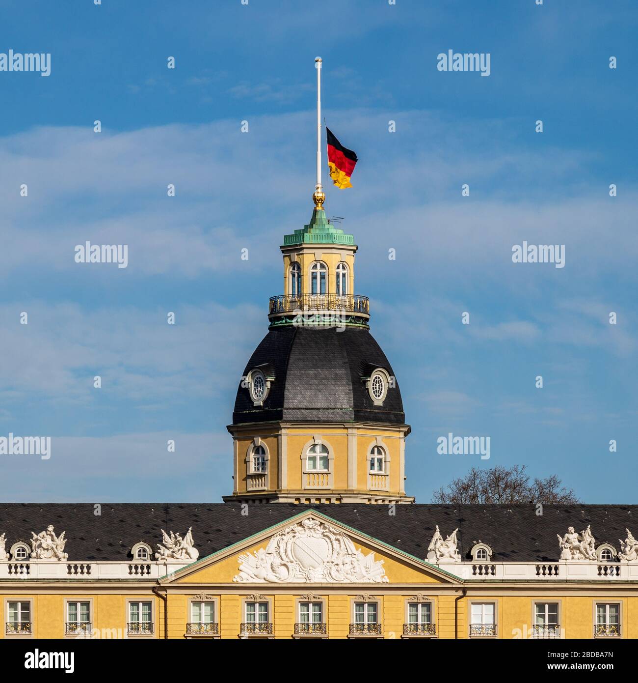 Deutsche Fahne am Halbmast, auf Halbmast, auf der Spitze von Schloss Karlsruhe im Winter. In Karlsruhe, Baden-Württemberg, Deutschland Stockfoto