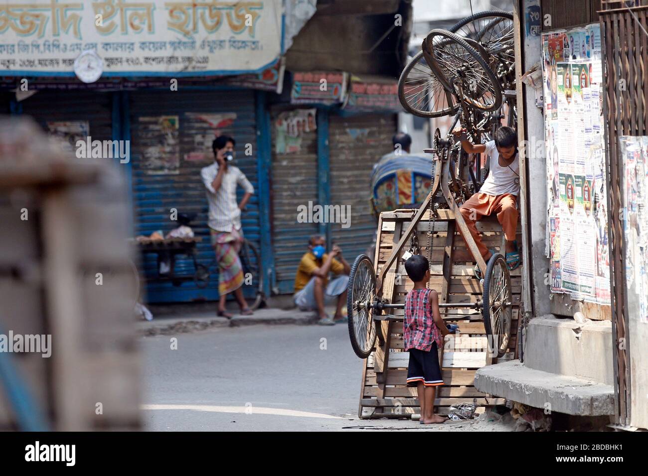 Während die Blockierung im ganzen Land andauert, kann selbst die geschäftige Gegend um Old Dhaka Bongshal einige faule Nachmittage erleben. Zwei Kinder spielen mit Rikscha-Van Stockfoto