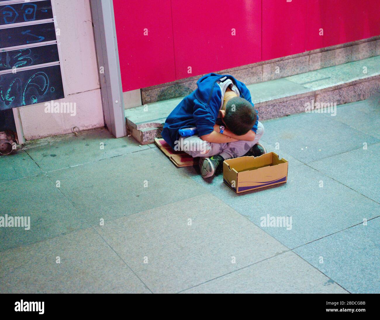 Bettlerjunge, der Junge, der nachts bei kaltem Wetter auf der Straße um Geld bettelte Stockfoto